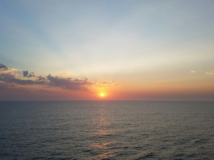 the sun is setting over the ocean on the horizon